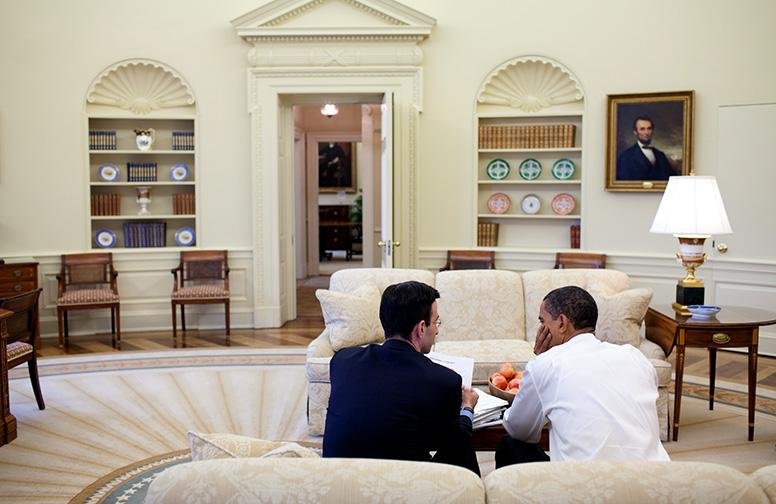 Peter Orszag and Barack Obama seated together reviewing papers in the Oval Office.